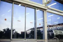 Puertas automáticas de cristal en una estación de transporte, con señalización naranja y bancos de espera metálicos a un lado.