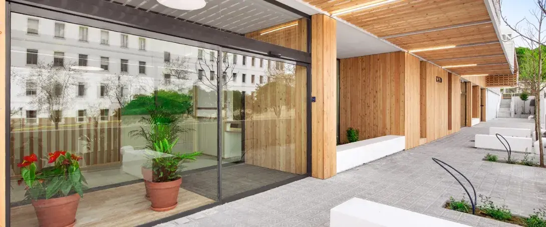 Door automatic sliding glass at the entrance of a modern building with timber façade and landscaped external access.