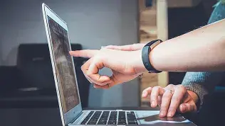 Two people reviewing technical information on a laptop during a work meeting.