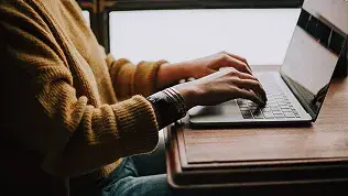 Person working with a laptop on administrative and technical management tasks.
