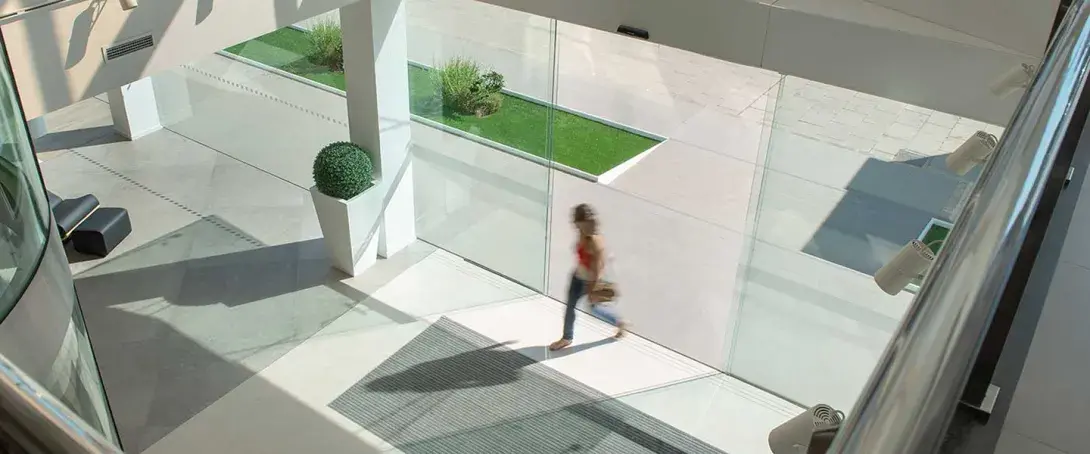 Person walking through a modern lobby with glass doors.