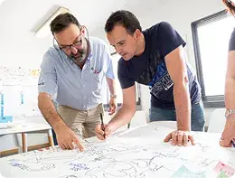Two technicians reviewing plans on a table.