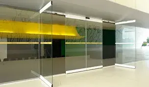 Puerta automática corredera de cristal con paneles plegables en el interior de un edificio moderno.